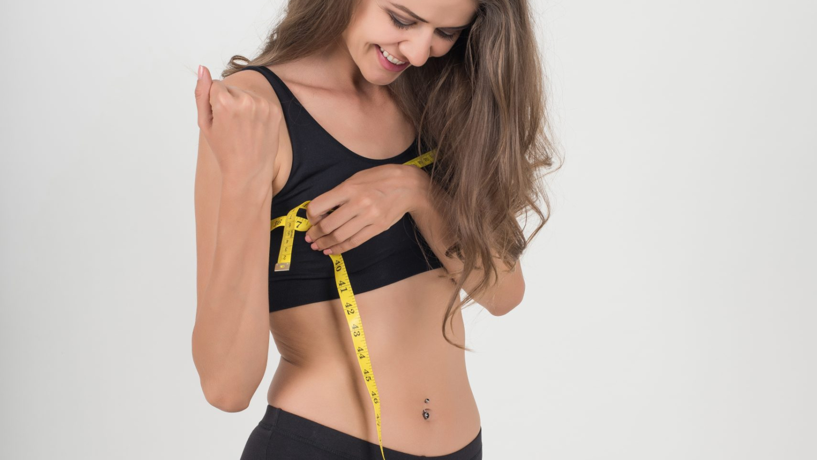 Portrait of beautiful young woman measuring her figure size with tape measure