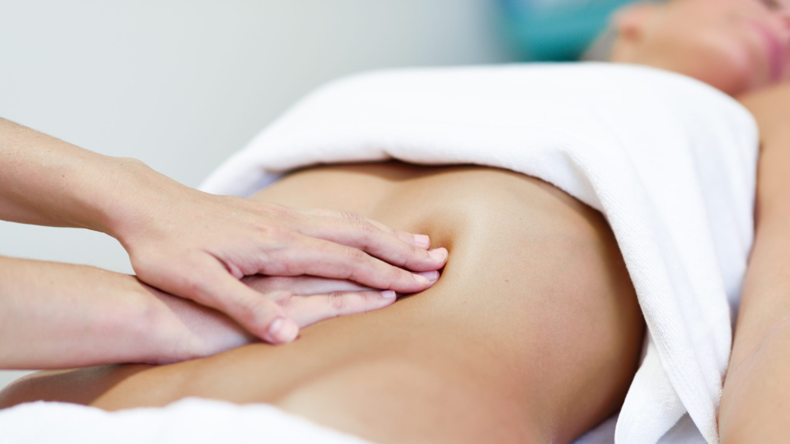 Hands massaging female abdomen.Therapist applying pressure on belly. Woman receiving massage at spa salon