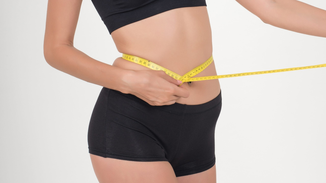 Portrait of beautiful young woman measuring her figure size with tape measure