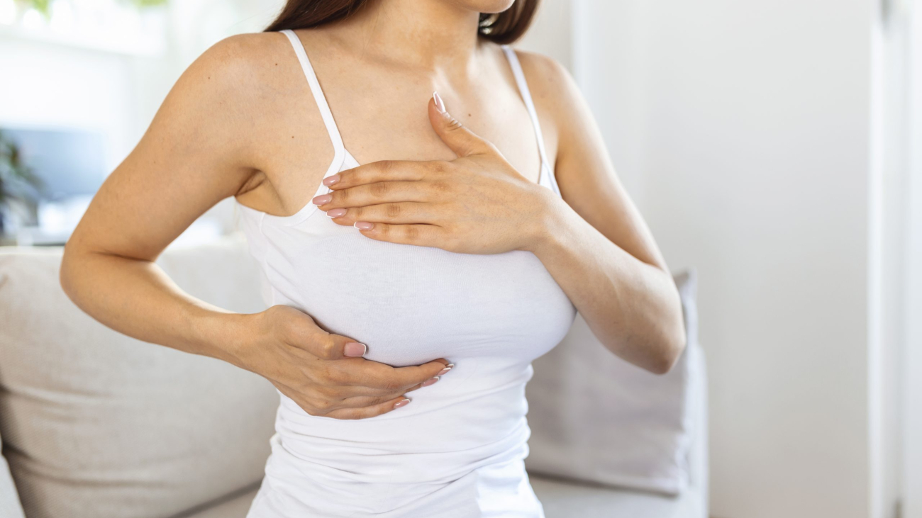 Young caucasian woman palpating her breast by herself that she concern about breast cancer. Healthcare and breast cancer concept